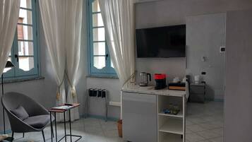 Een kleine kamer met een bed, bureau, stoel, televisie en garderobe.