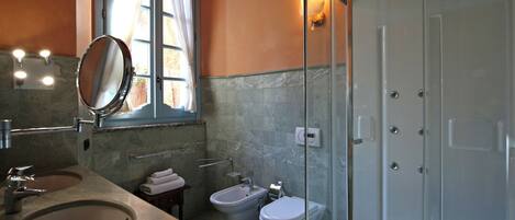 A bathroom with a sink, mirror, bidet, toilet, and a shower enclosure.
