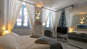 A bedroom with a bed, a chair, a TV, and a painting on the wall. - Palazzo del Vicerè  (Lezzeno)