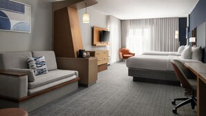 A modern hotel room with a sofa, a desk, a bed, a TV, and a large window with curtains. - Courtyard Hammond (Hammond)