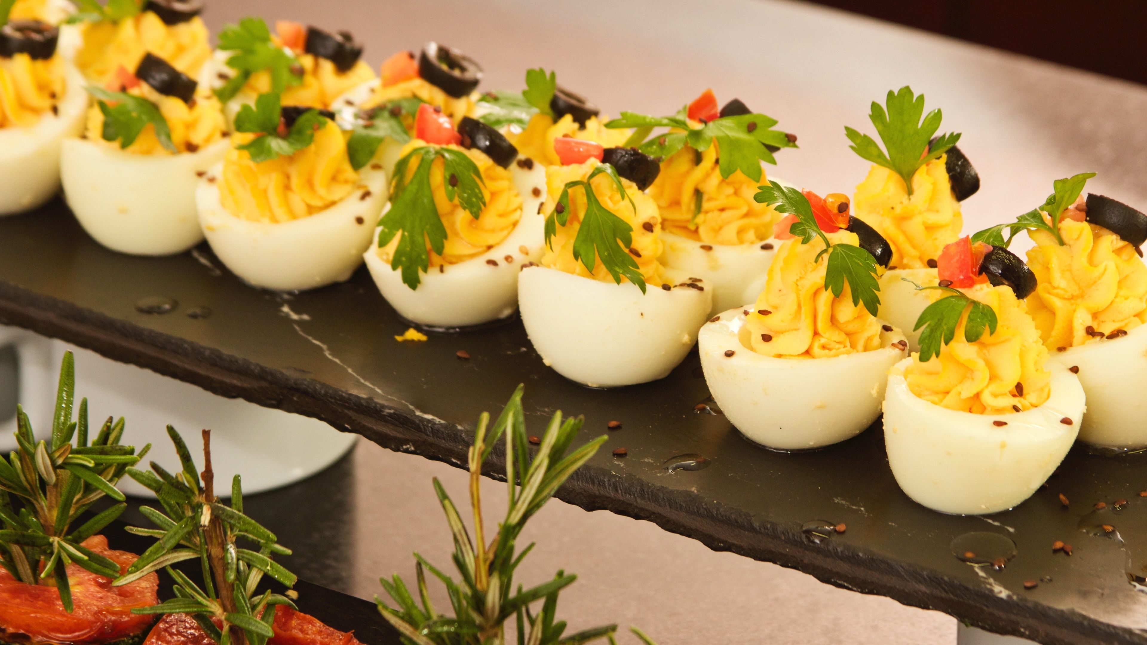 A tray of deviled eggs garnished with parsley and black olives.