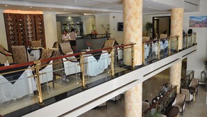 A hotel lobby with a glass railing, multiple seating areas, and a reception desk.