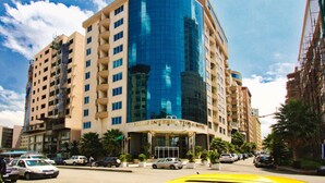 A hotel with a curved glass facade, multiple floors, and a prominent entrance.
