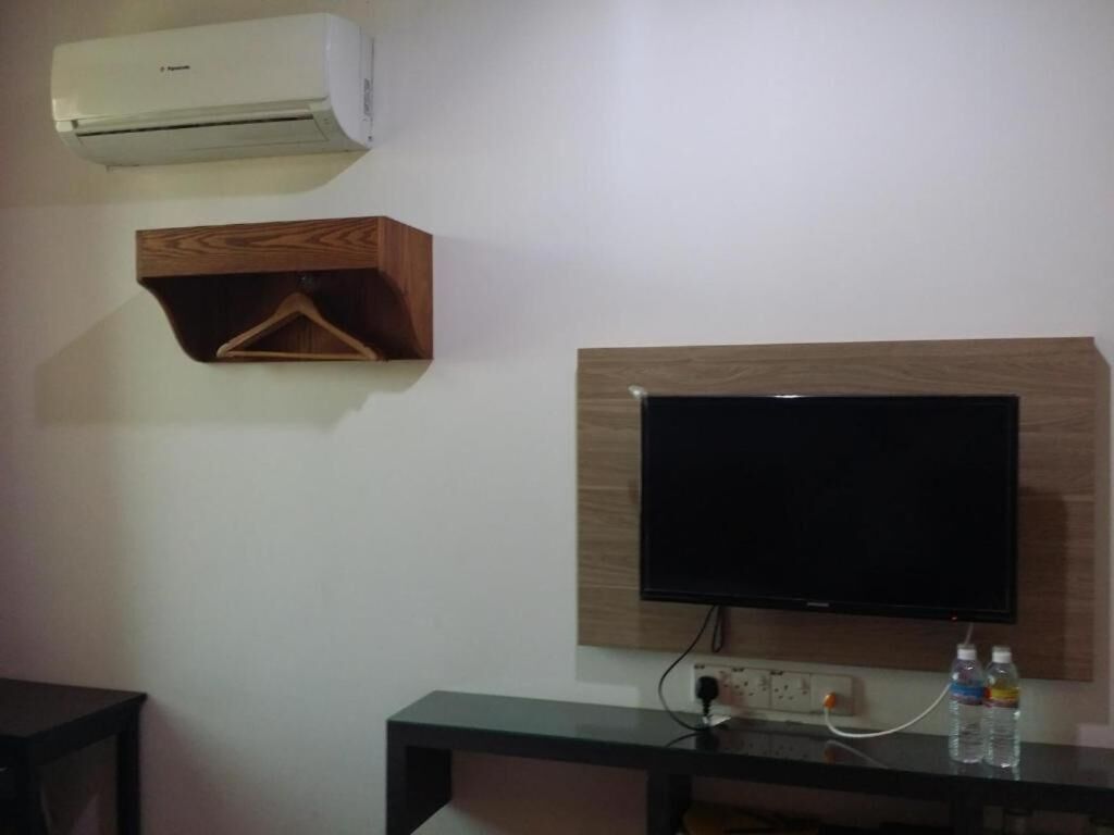 Ein Zimmer mit einem an der Wand befestigten Flachbildfernseher, einem Holzregal und einer Klimaanlage.