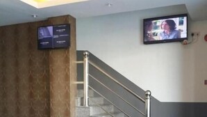 A lobby with a leather sofa, a staircase, and a television mounted on the wall.