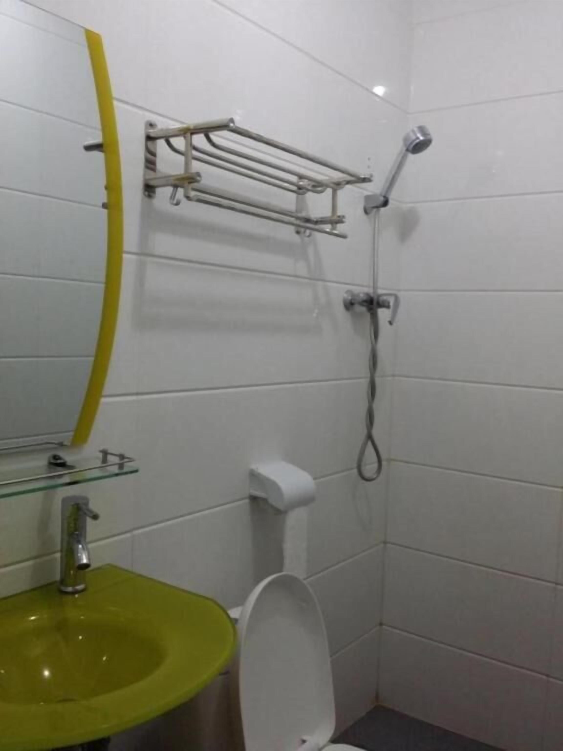 A small bathroom with a green sink, a toilet, and a shower.