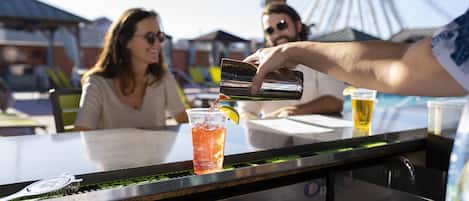 A bar area with a stainless steel counter and a person pouring a drink into a glass.