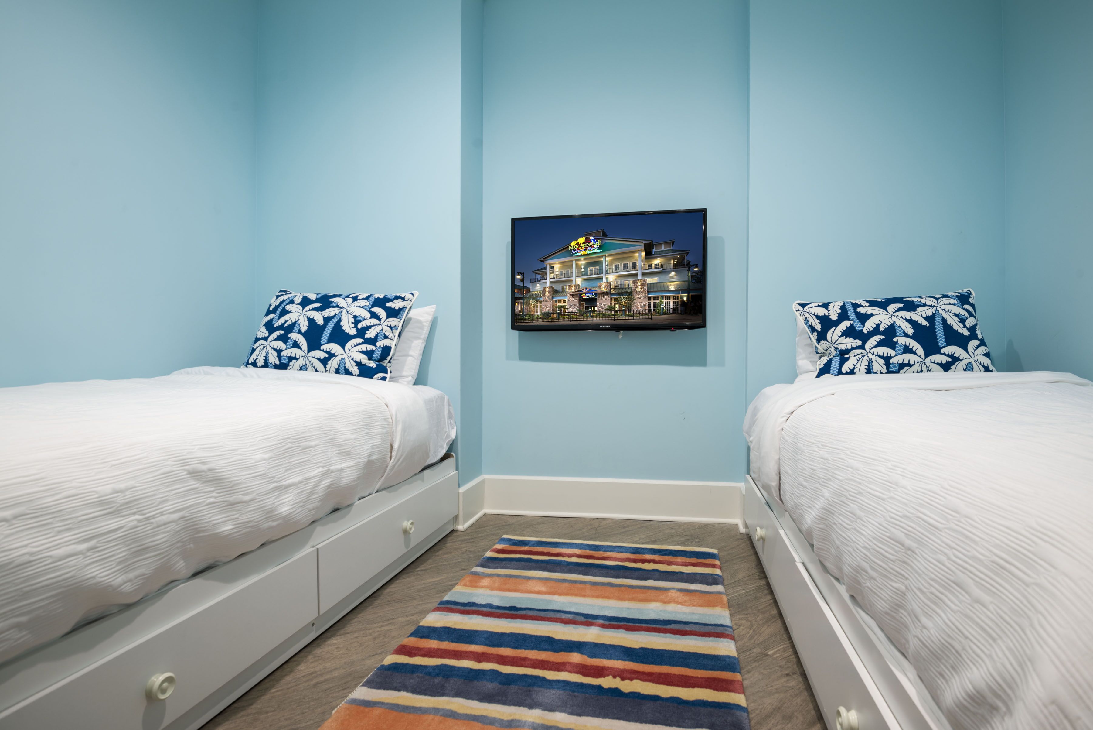 A bedroom with two beds, a colorful striped rug, and a framed picture on the wall.