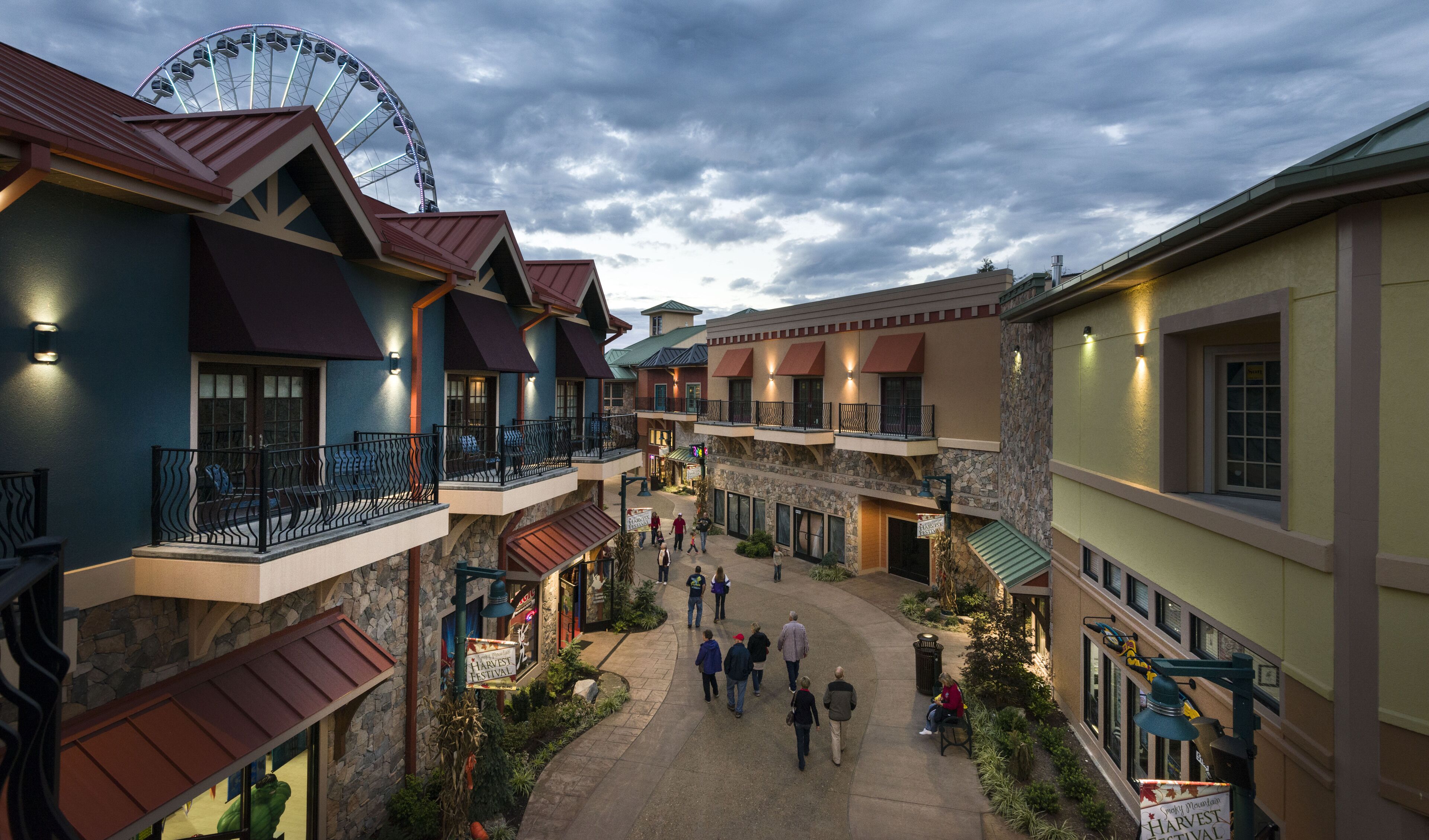 A courtyard with a Ferris wheel, multiple buildings with balconies, and a Harvest Festival sign.