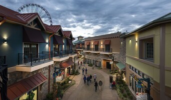 Un patio con noria, varios edificios con balcones y un cartel anunciando la Fiesta de la Cosecha.