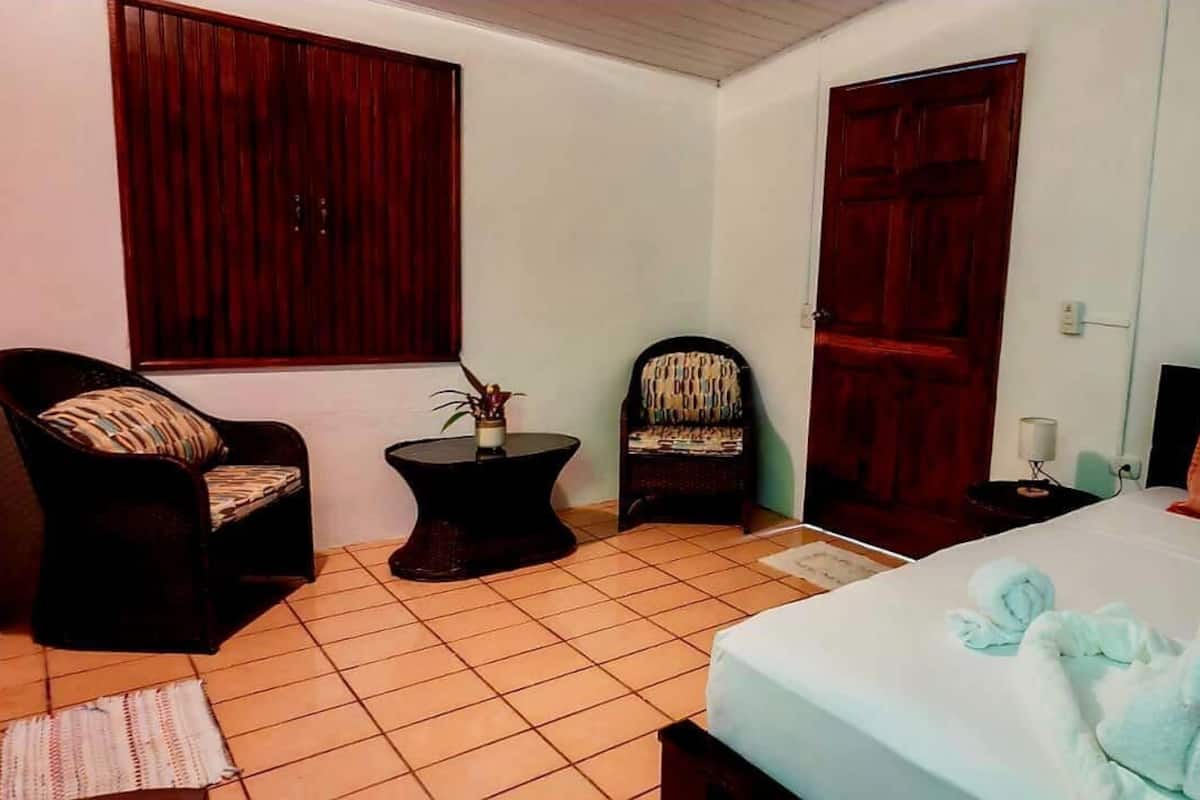 A bedroom with a bed, a chair, a small table, and a wardrobe.