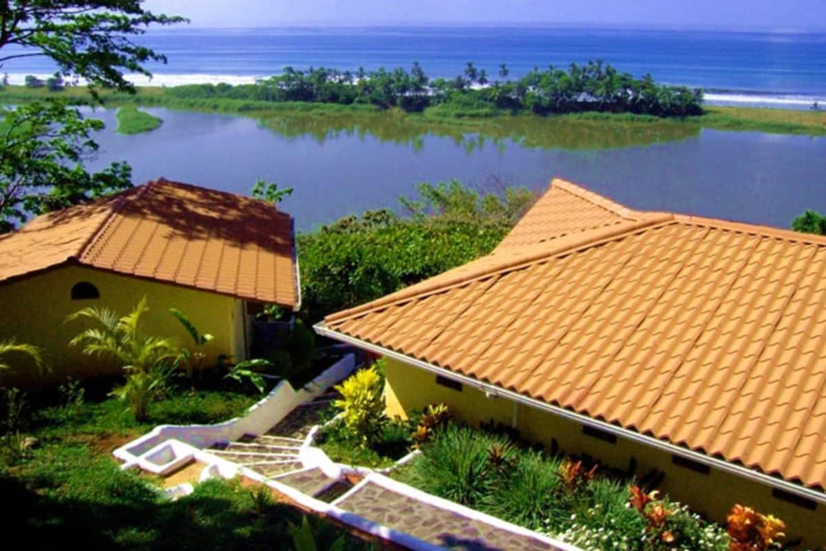 A coastal property with a tiled roof, a small building, and a view of the ocean.