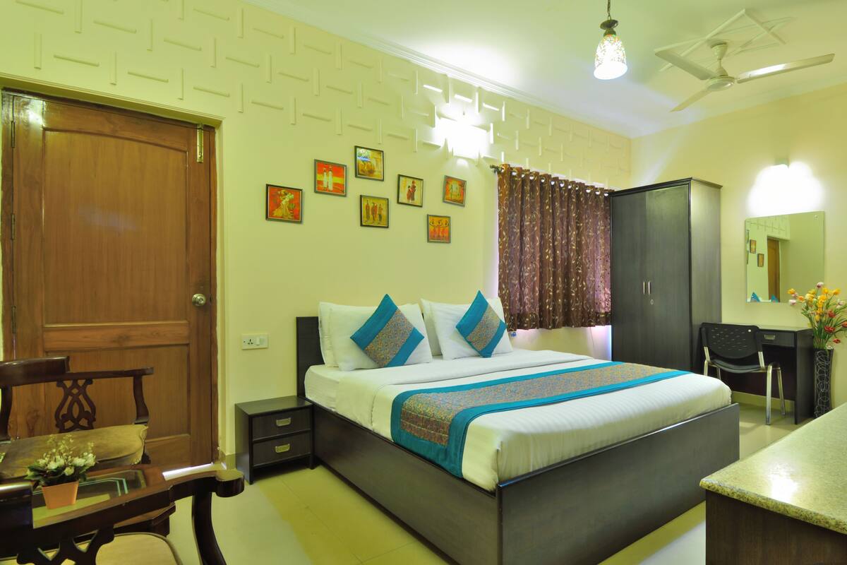 A neatly arranged bedroom with a bed, bedside tables, a desk, and a chair.