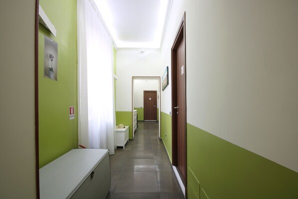 A hallway with green walls, a white bench, and a door at the end.