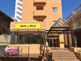 Exterior del Hotel Smile con una entrada despejada, una escalera que conduce a la entrada y una planta de cactus en primer plano.
