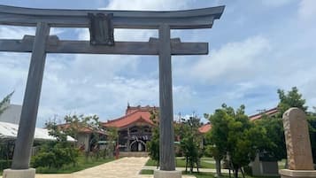 Un torii japonés tradicional con un monumento de piedra a su lado, que conduce a un edificio de techo rojo.
