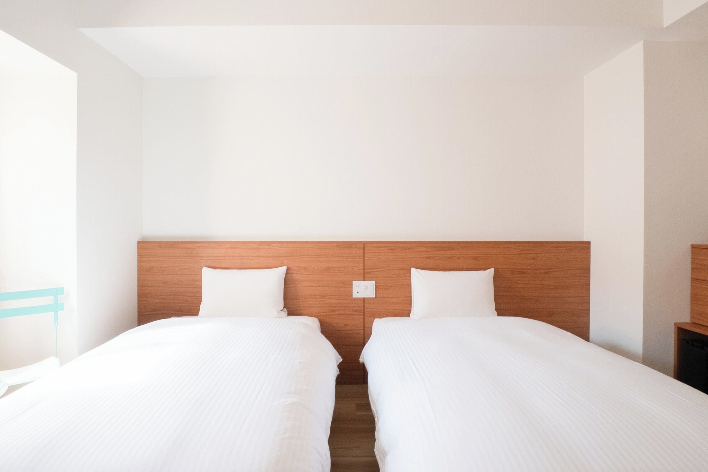 A hotel room with two single beds, a wooden headboard, white bedding, and a small bedside table.
