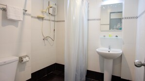Ein Badezimmer mit Dusche, Toilette, Waschbecken und Spiegel.