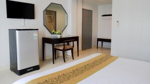 Ein Hotelzimmer mit Bett, Schreibtisch, Stuhl, Kühlschrank, Fernseher und Spiegel.