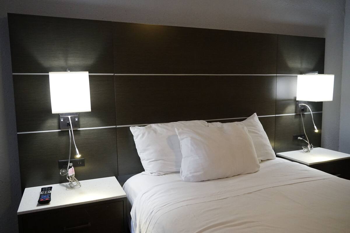 A hotel room with a large bed, two bedside tables, and two wall-mounted lamps.