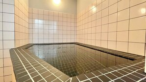 A swimming pool with a tiled floor and walls, a ceiling light, and a bench along the edge. - Hotel Mayflower Sendai (Sendai)