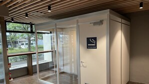 A smoking room with a glass door, a fire extinguisher, and a view of the outside. - Hotel Mayflower Sendai (Sendai)