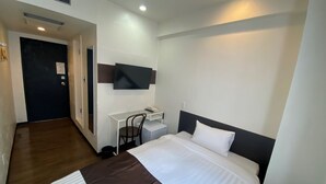 A hotel room with a bed, a desk, a chair, a TV mounted on the wall, and a door. - Hotel Mayflower Sendai (Sendai)