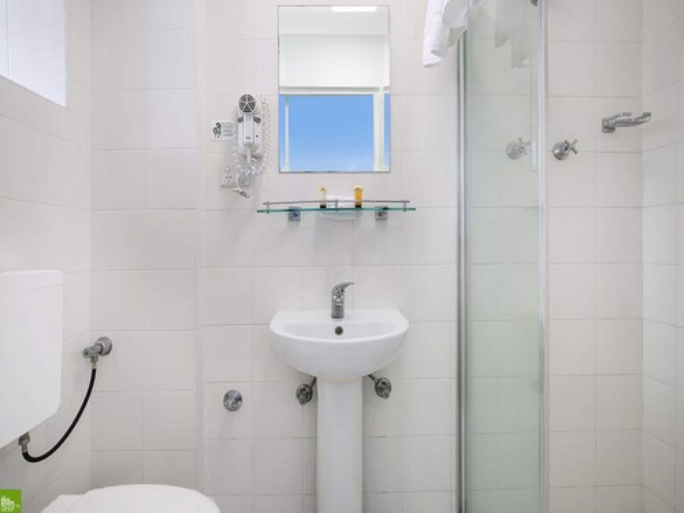 A bathroom with a white sink, a glass shower enclosure, and a mirror above the sink.