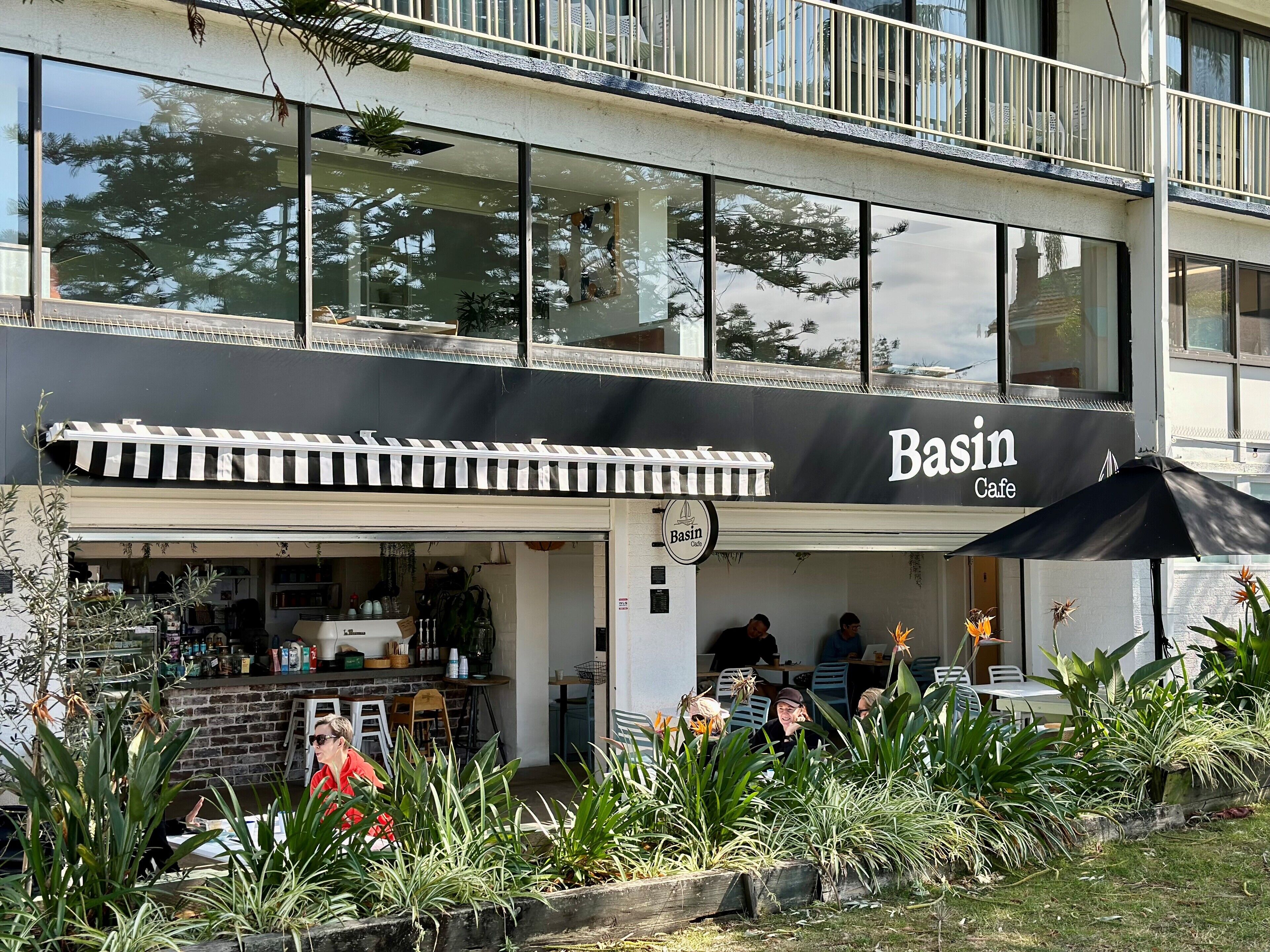 Een café genaamd 'Basin Cafe' met terras en een zwart dakzeil.