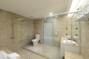 Un baño moderno con ducha de vidrio, inodoro y tocador con espejo.