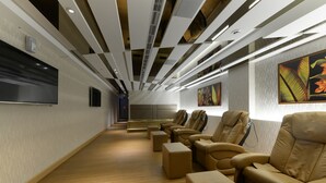Un interior moderno con una hilera larga de sillones de cuero, un televisor de pantalla plana en la pared y obras de arte decorando las paredes.