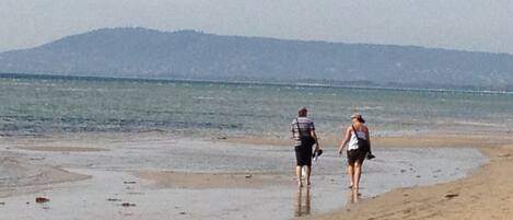 A beach with two people walking along the shore.