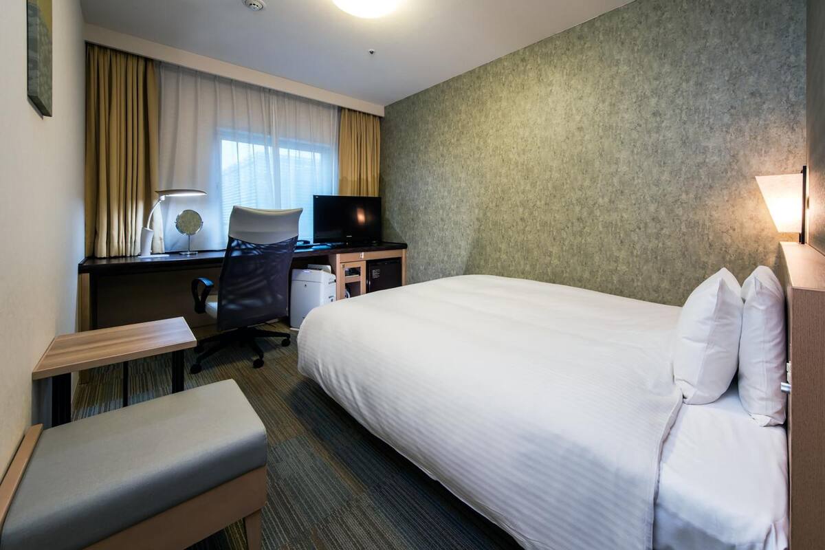 Ein Hotelzimmer mit Bett, Schreibtisch, Stuhl und kleinem Tisch.