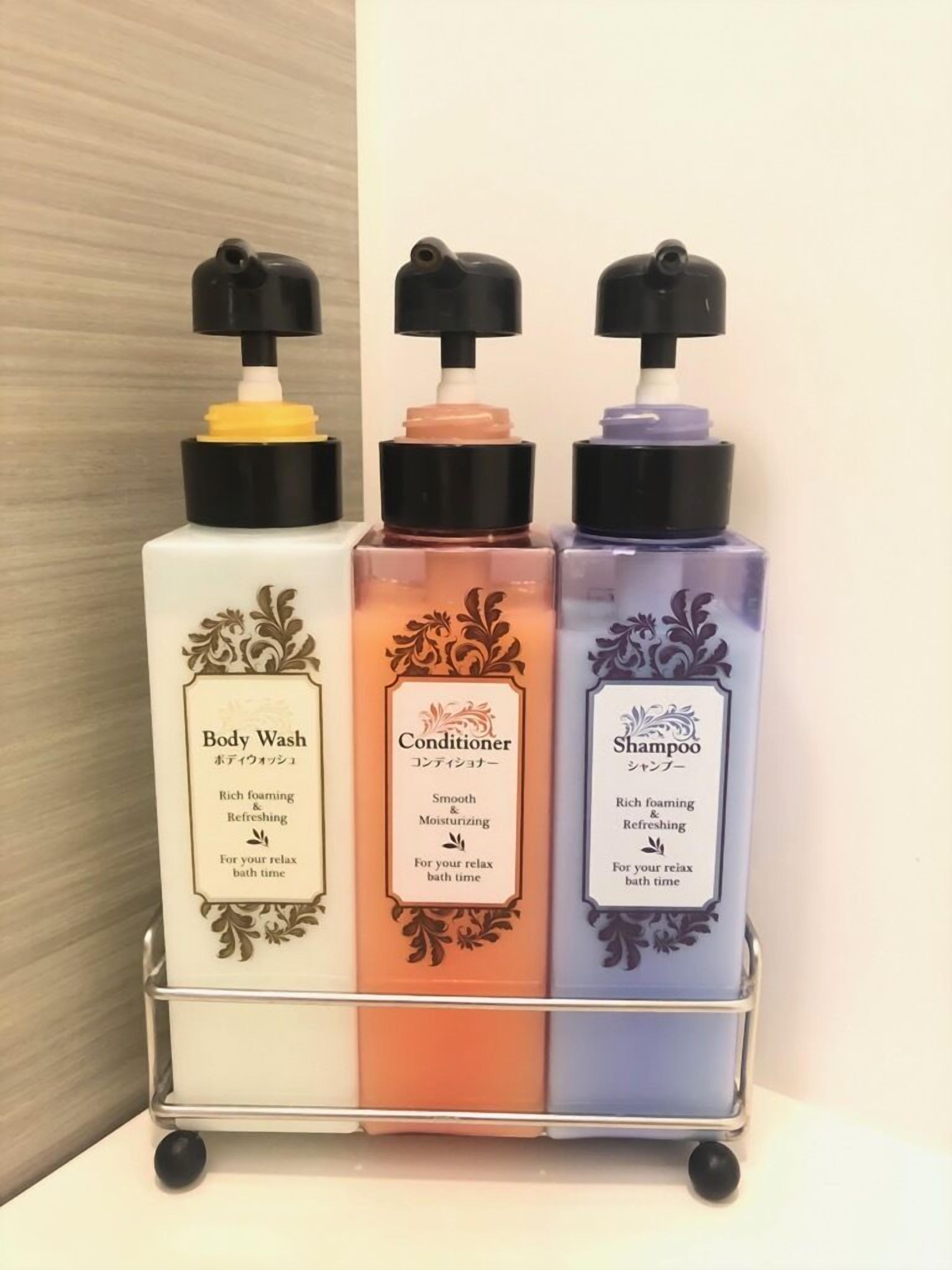 A metal cart with three bottles of body wash, conditioner, and shampoo.