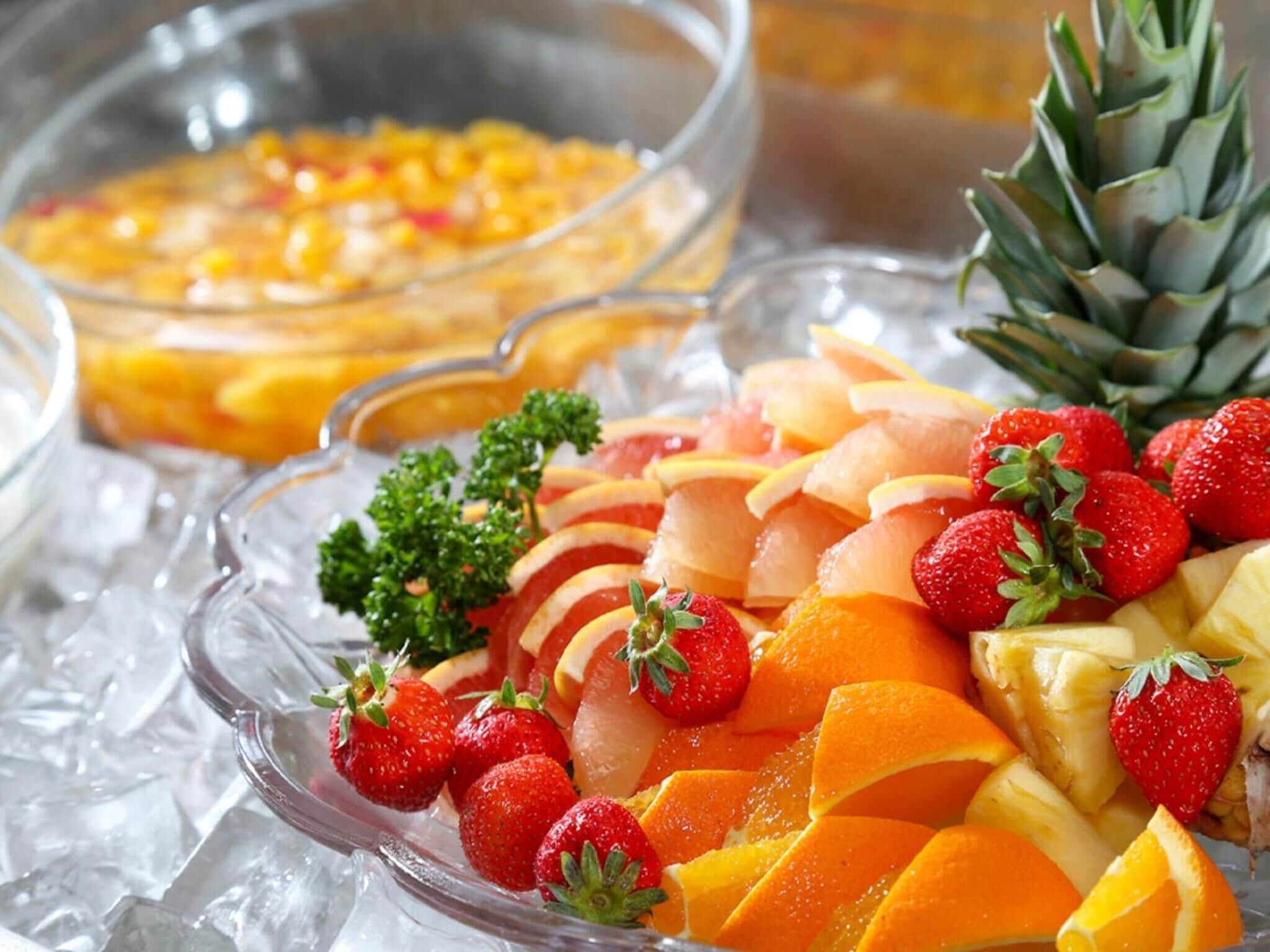 A buffet with sliced fruits and a pineapple.