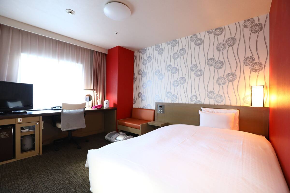 Ein Hotelzimmer mit Bett, Schreibtisch, Stuhl und Fernseher.