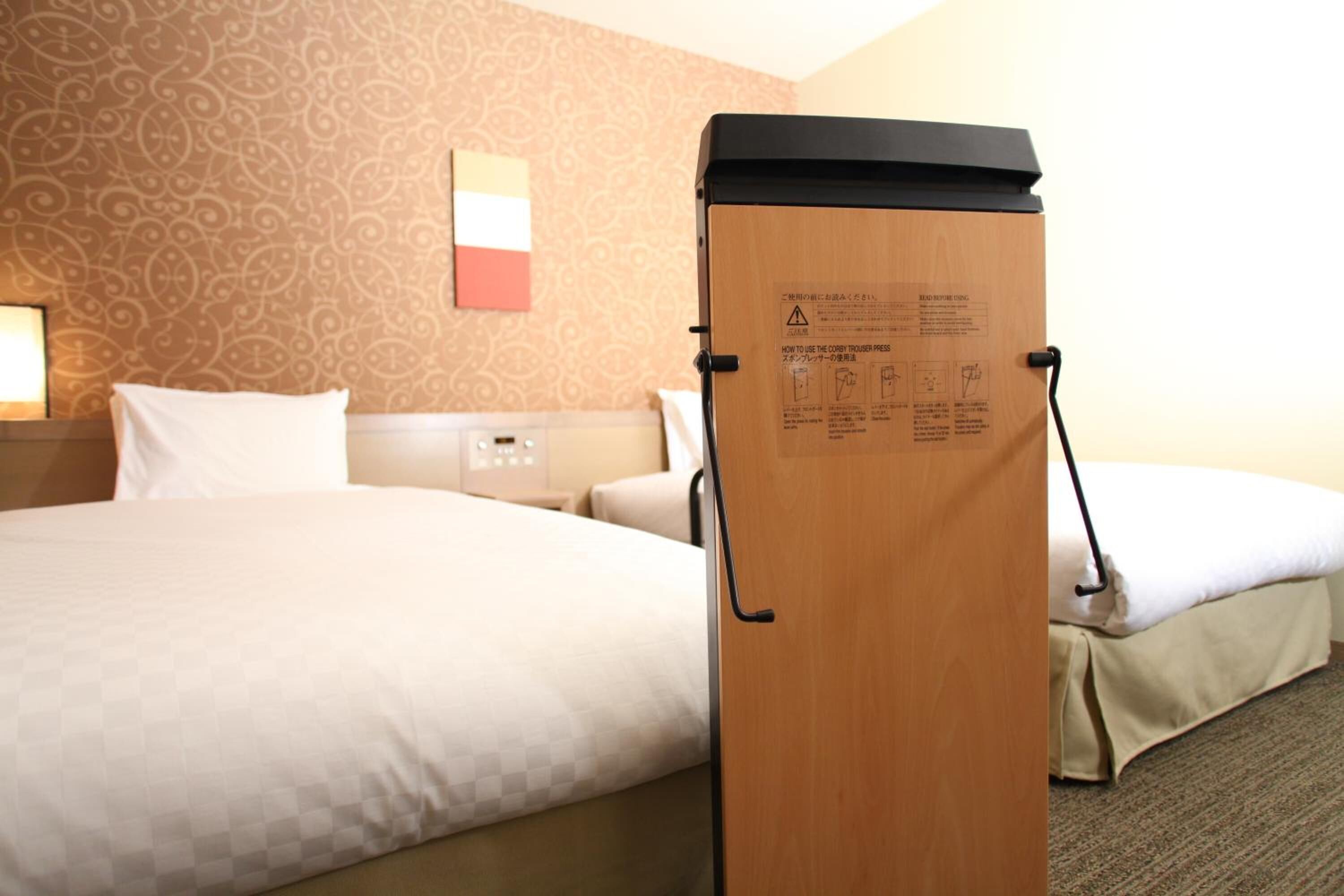 Una habitación de hotel con una cama, un armario de madera con instrucciones y un papel tapiz estampado.