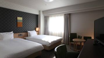 A hotel room with two beds, a desk with a television, a small round table, and a chair.