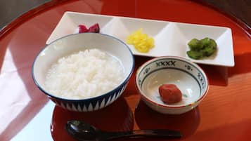 Una mesa con un tazón de arroz blanco, un plato pequeño con un elemento rojo, y dos platos pequeños con elementos amarillos y verdes.