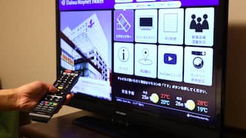 Een televisiescherm toont een interface voor het boeken van een hotel, met een afstandsbediening in de hand.
