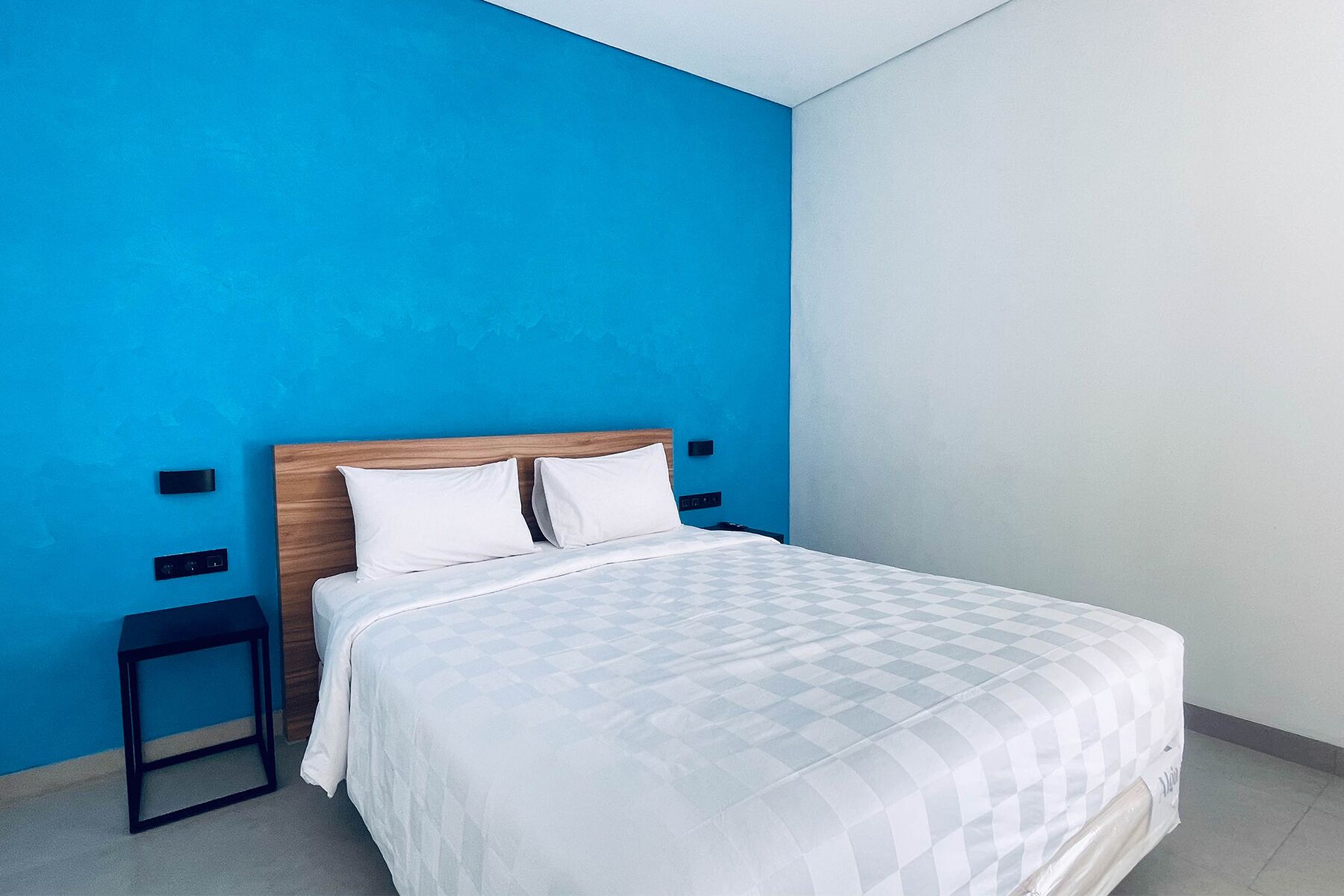 A bedroom with a bed, a nightstand, and a wall-mounted light fixture.