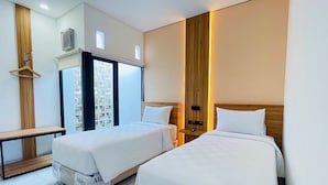 A hotel room with two beds, a wooden wardrobe, a bench, and a large window with blinds. - Alfa Jivana Resort  (Cisarua)