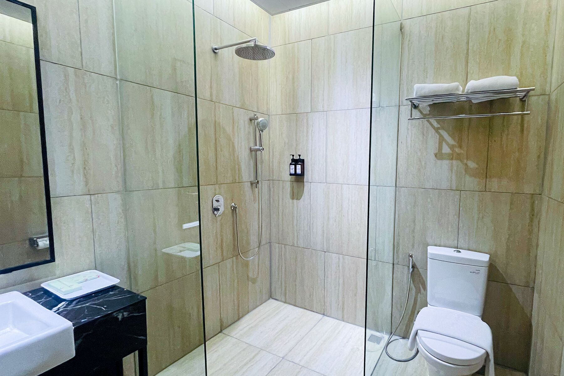 Une salle de bain moderne dotée d’une douche à parois de verre, de toilettes et d’un lavabo.