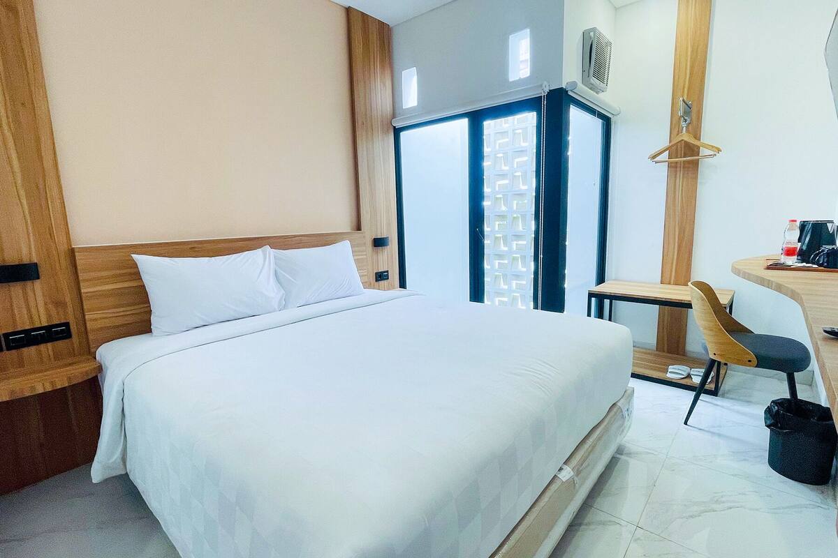 Ein Hotelzimmer mit einem großen Bett, einem Schreibtisch, einem Sessel und einem kleinen Tisch.
