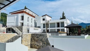 A modern multi-story building with a stone facade, a covered outdoor area, and a staircase leading to the upper levels. - Alfa Jivana Resort  (Cisarua)