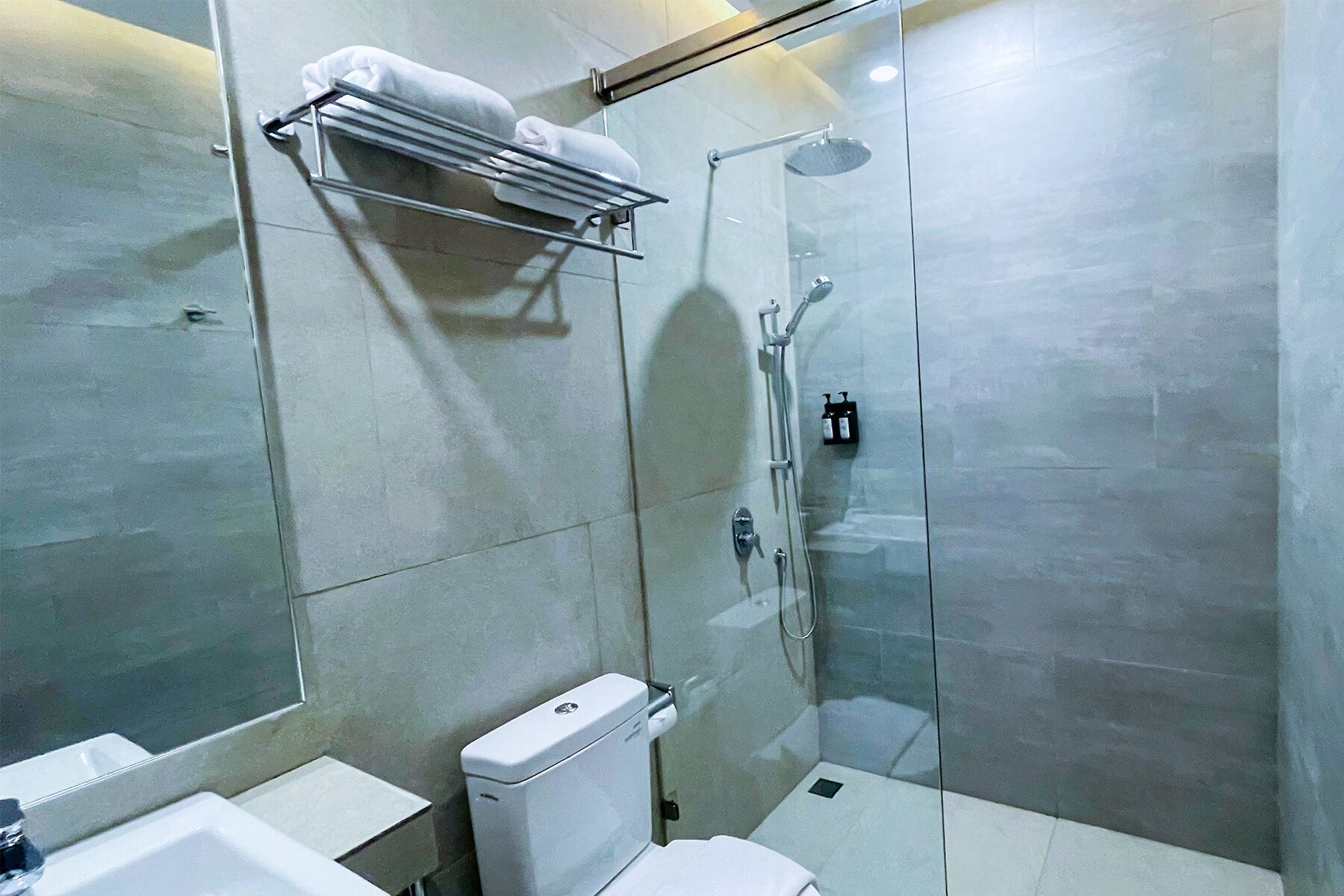 Un baño moderno con ducha envuelta en vidrio, inodoro y lavamanos.