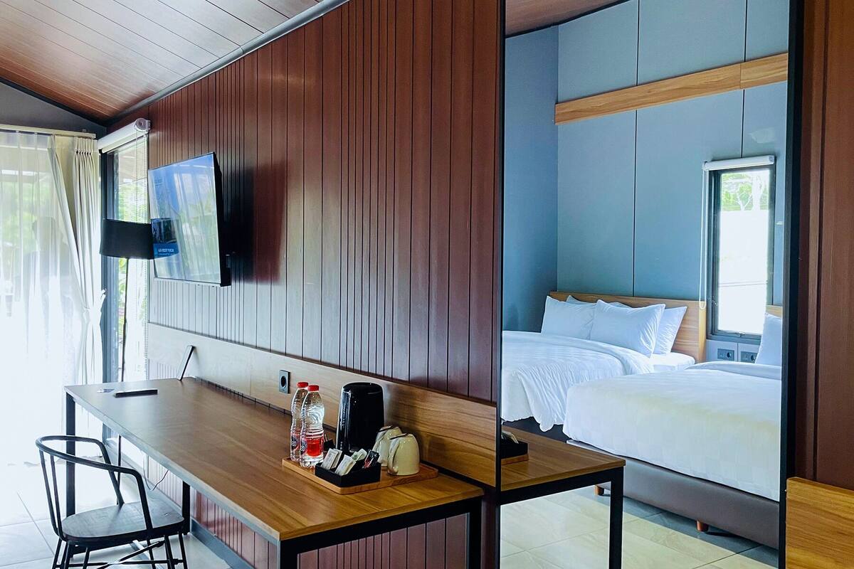 Ein Hotelzimmer mit einem hölzernen Schreibtisch, einem Bett und einem an der Wand montierten Fernseher.