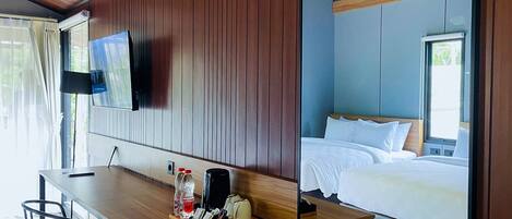 Una habitación de hotel con un escritorio de madera, una cama y un televisor montado en la pared.
