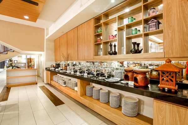 A modern kitchen with wooden cabinets, a black countertop, and neatly stacked plates.