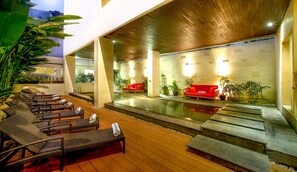 A pool area with lounge chairs and a red sofa. - Euphoria Hotel (Legian)